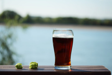 glass of beer on the table by the river