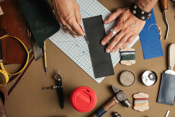 Tools and equipment for leather handmade goods. Cropped image of a male artisan making custom made...