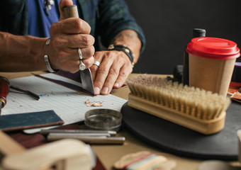 Leather goods master hands cutting piece of natural leather with crafting tool. Workflow in the...