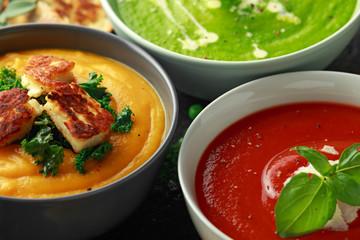 Variety of cream soup bowls: sweet pea and mint, tomato and basil and butternut squash with steamed kale and fried halluomi