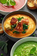 Variety of cream soup bowls: sweet pea and mint, tomato and basil and butternut squash with steamed...