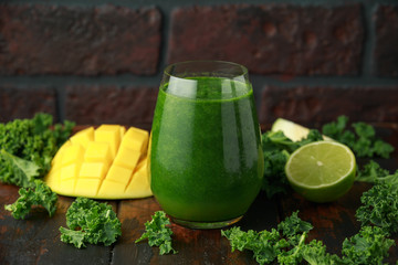 Green smoothies with kale and mango on wooden table