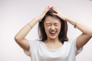 Close up isolated portrait of young extremely upset and frustrated Asian woman pulling her hair and...