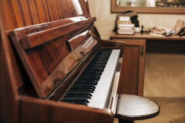 Fototapeta na wymiar A beautiful vintage piano with an open lid is at home to work on a piano. The piano keys are ready to play on them