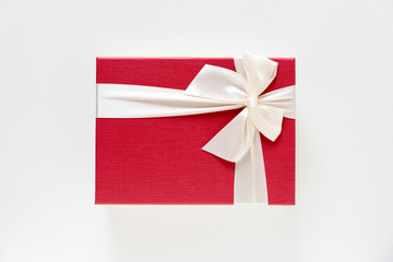 red giftbox with white bow strip on white background , top view
