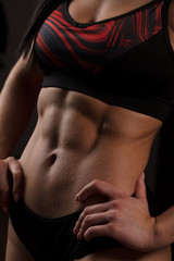 Close up of fit female abs isolated on black background with copy space. Fitness female and trained...