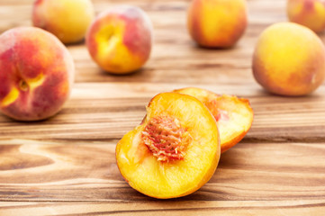Fototapeta na wymiar Halves of peaches with whole peaches on wooden background.