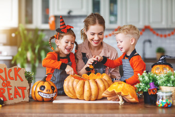 happy Halloween! family mother and children getting ready for holiday cutting pumpkin