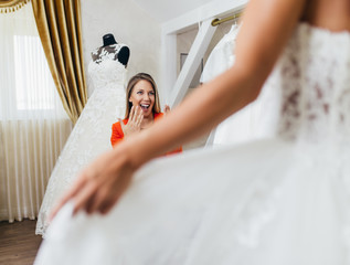 Beautiful young brunette woman choosing wedding dress in a bridal salon.