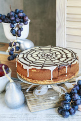 Halloween chocolate spider web cake and various fruits around.
