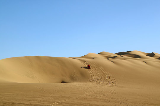 A red dune buggy running on the immense sand dune of Huacachina, Ica region, Peru 