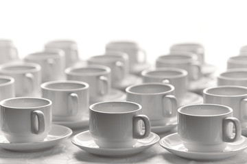 White cups for tea  stacked in line on table with tablecloth for coffee-break.