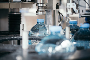 Industrial factory indoors and machinery. Robotic factory line for processing and bottling of pure spring water into canisters and bottles