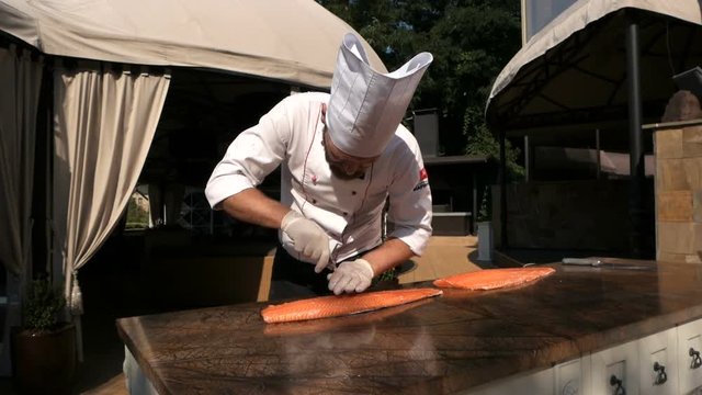 Chef is removing fish bone from salmon with tweezer