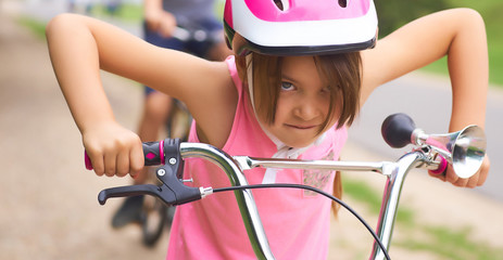 Naklejka premium Portrait of a litte girl in a pink safety helmet driving her bike.