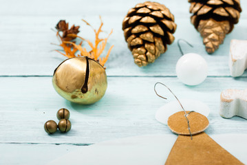 handmade angel from paper, rocking horse and golden cones on bright wooden, soft light