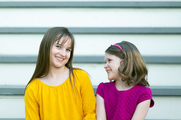 Sisters Sitting on Outdoor House Stairs Laughing and Telling Secrets