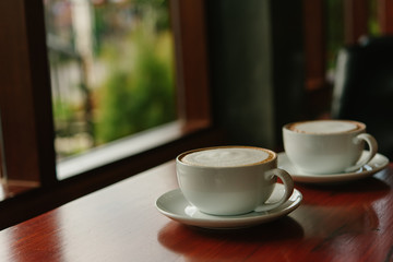 Hot Coffee in a cup on wooden table and morning light