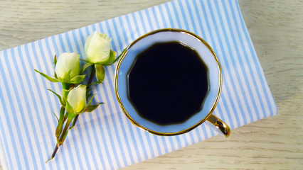Fragrant coffee and white roses on a blue napkin.