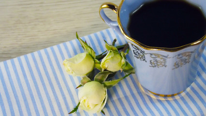 Fragrant coffee and white roses on a blue napkin.