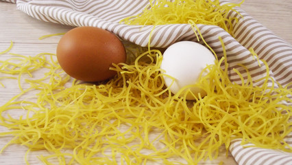 Homemade egg noodles and eggs on light wooden background.