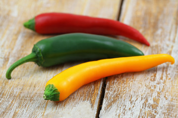 Yellow, red and green chilli peppers on rustic wooden surface
