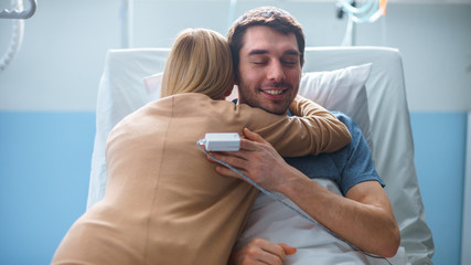 In the Hospital, Man Recovering from Illness Lying in Bed, Loving Wife Visits Him. They Embrace and...