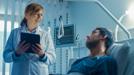 In the Hospital, Friendly Female Doctor Checks on the Sick Male Patient Lying in Bed. They Have...