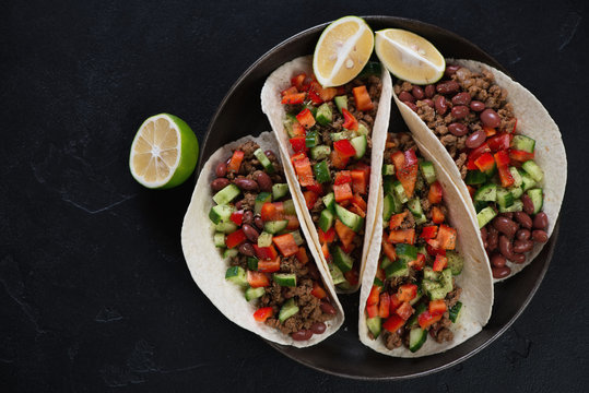 Above view of a metal tray with mexican tacos over black stone background, horizontal shot
