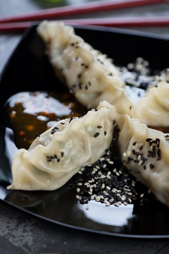 Close-up of steamed korean dumplings with sesame seeds on a black plate, selective focus