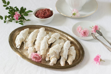 Traditional Romanian or Moldavian shortcake cookies with jam stuffing and a cup of tea on the light background.