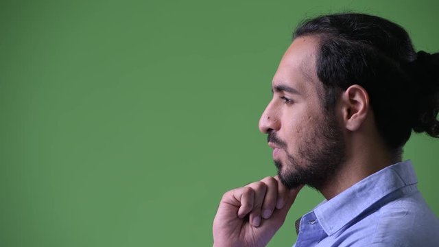 Profile view of young handsome bearded Indian businessman thinking