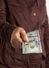 Paper notes from USA. Dollar. Front view senior person holding bills.
