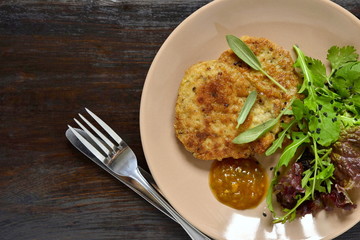 Fried pork chop with fresh herbs and fruit sauce, top view, copy space