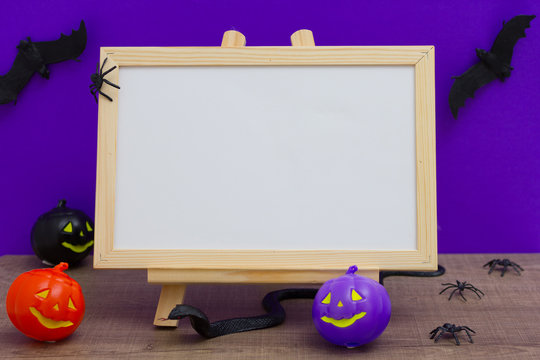 Halloween background concept. white board with decor pumpkin, bat, snake spider, cobweb on purple backdrop