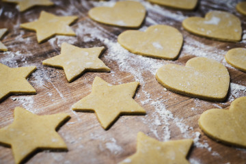 Fototapeta na wymiar Christmas baking. Making gingerbread biscuits. Cookie dough in heart and star shape on kitchen counter.