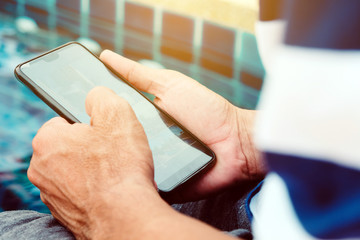 Modern man using cellphone on the pool.