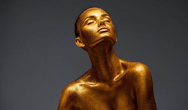 Golden skin beauty woman portrait. Fashion model girl with holiday golden makeup. Body art