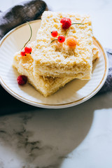 Pieces of cottage cheese cake with a crumble decorated with raspberries and red currants on a white plate