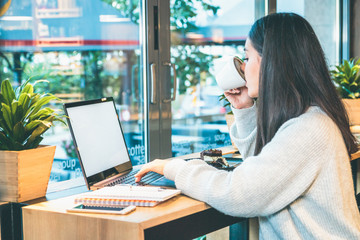 Obraz premium Side view of a woman working on laptop and drinking coffee at the same time - People concept