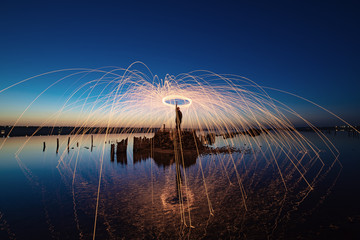 Amazing fireshow performance in the night blue sky with reflections in the sea water