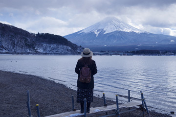 Fototapeta na wymiar Woman is looking at Mt/ Fuji view at Lake Kawakuchiko in Japan during winter.