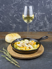 wine and Italian pasta with chicken in a black frying pan