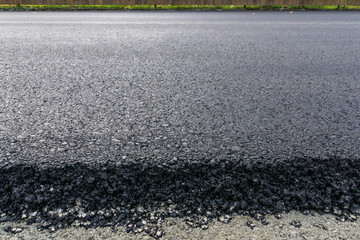 newly laid black bitumen asphalt with a high edge to the gravel