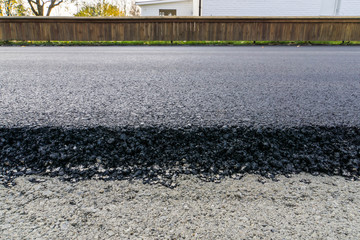 newly laid black bitumen asphalt with a high edge to the gravel