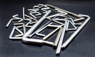 A lot of allen keys lying on a black, shiny table, front view. © Michal