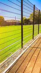 road near lawn field for playing minifootball behind the green fence mesh