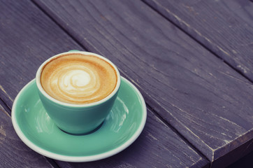 Turquoise cup from latte on a wooden background.
