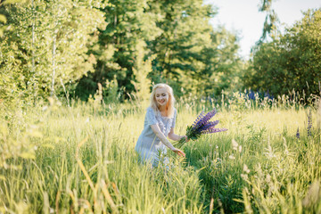 Girl with blonde hair in a long dress with a bouquet of flowers