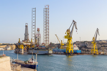 Fototapeta na wymiar Senglea, Malta. Offshore drilling platforms and ships in the territory of the shipyard in French Creek Bay